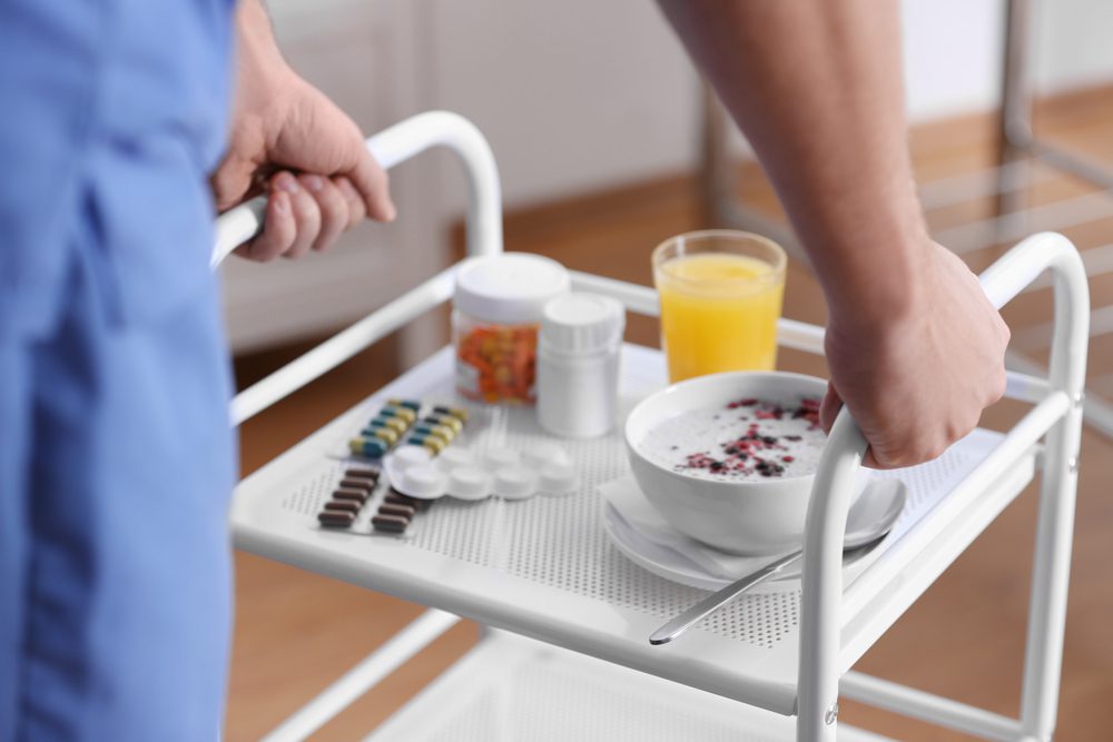 Nurse,Bringing,Patient's,Food,And,Medicine,On,Serving,Trolley,,Closeup.